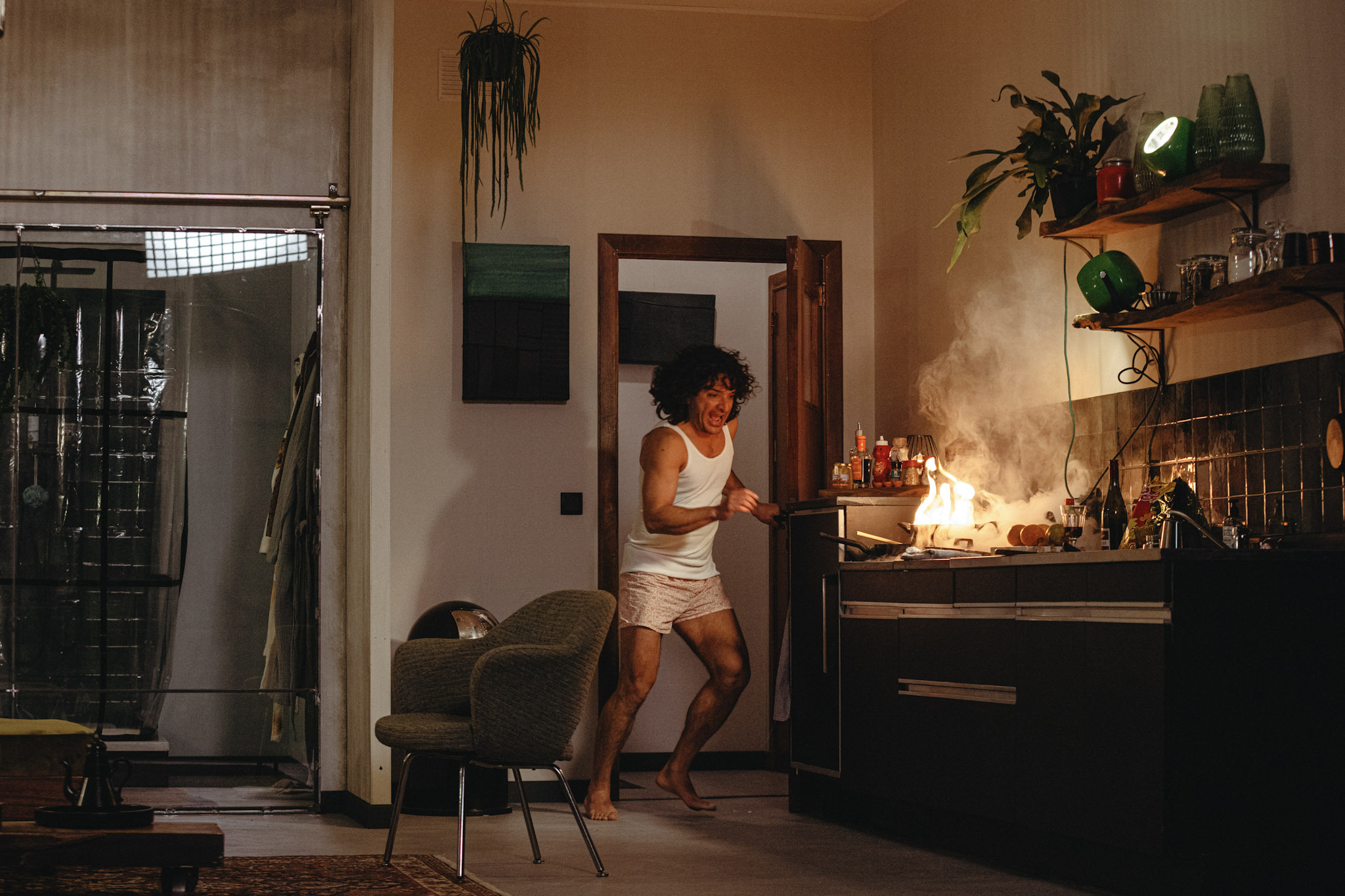 A person in their underwear holding a burning pan