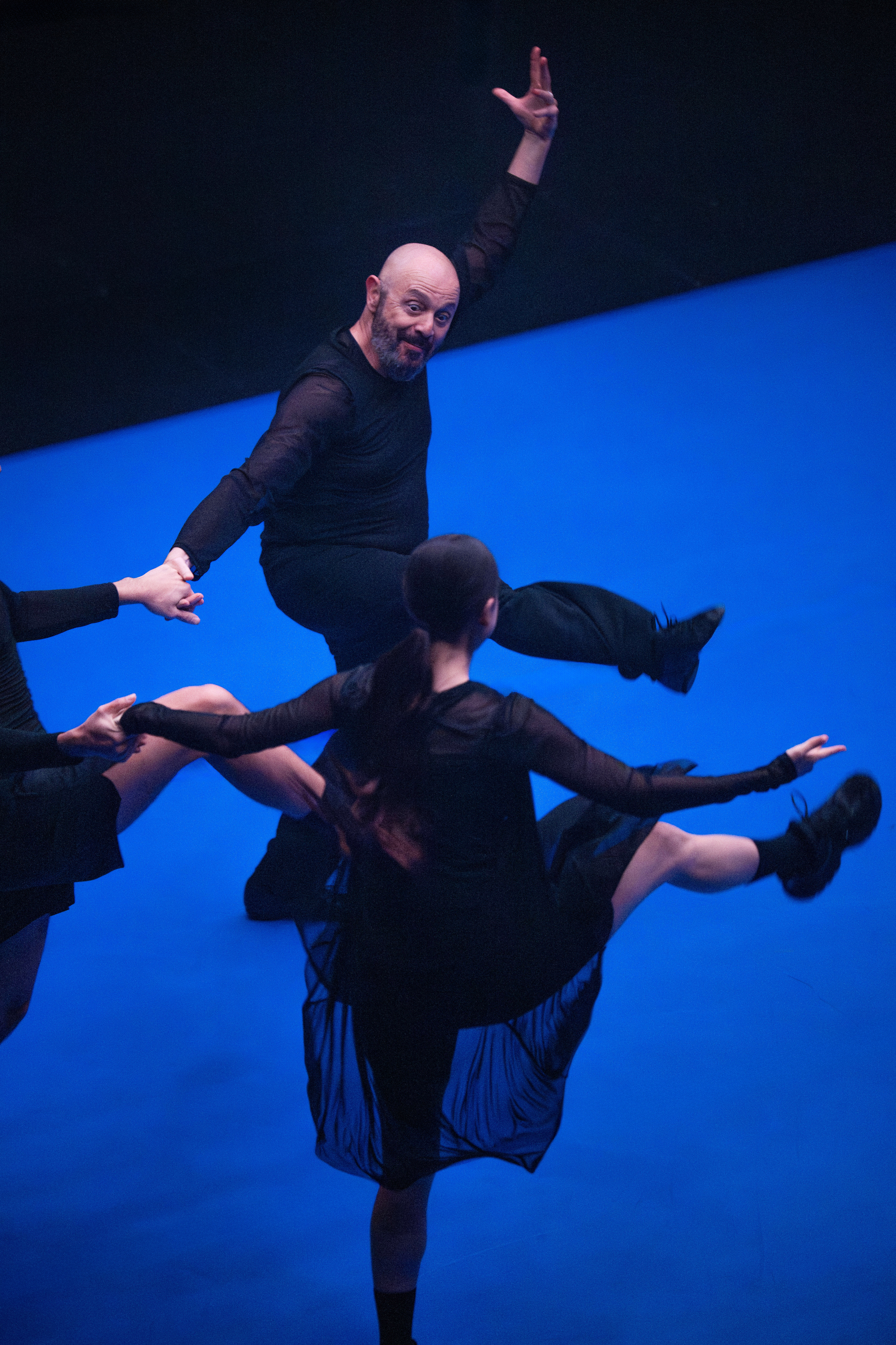 3 performers with black clothes dancing on a bright blue floor