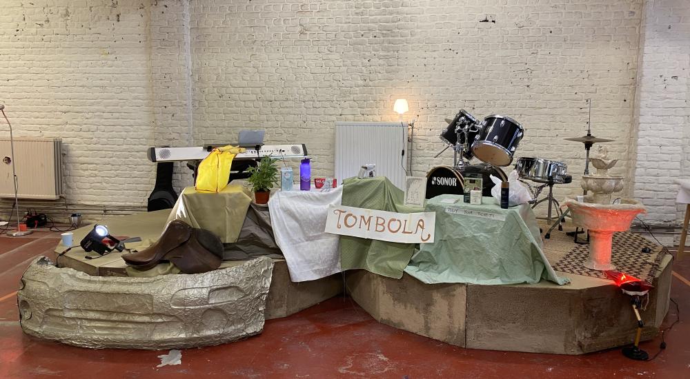 a double stage with a keyboard and drumset on it and a banner reading TOMBOLA