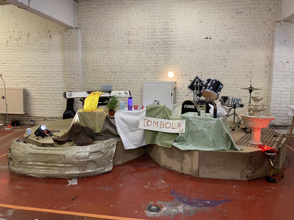 a double stage with a keyboard and drumset on it and a banner reading TOMBOLA